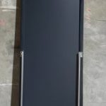 Back of a full-length mirror showing the black backing board and rear struts